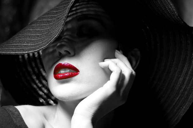 Portrait of mysterious beautiful young woman with wonderful skin texture in black hat. Trendy glamorous fashion makeup. Sensual red lips. Black and white image. Art photo